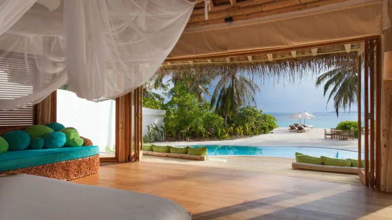 Nine-bedroom Private Reserve villa interior with thatched roof and beach frontage at Soneva Fushi.