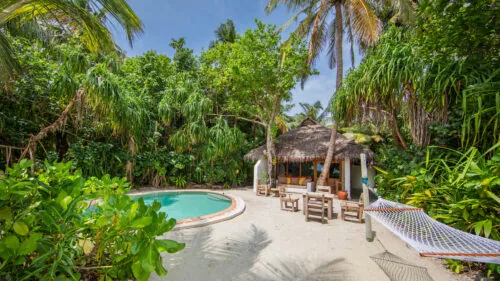 Villa 30 two-bedroom Soneva Fushi Villa with pool, sandy ground under palms at Soneva Fushi.