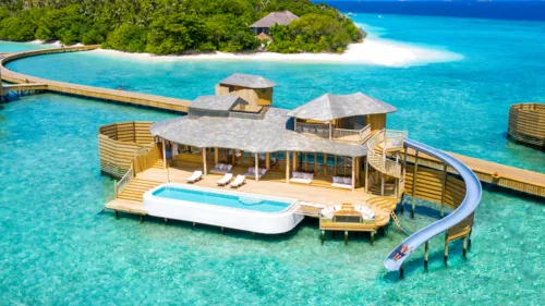 Over-water Water Reserve villa with curved waterslide spiralling down to turquoise lagoon at Soneva Fushi.