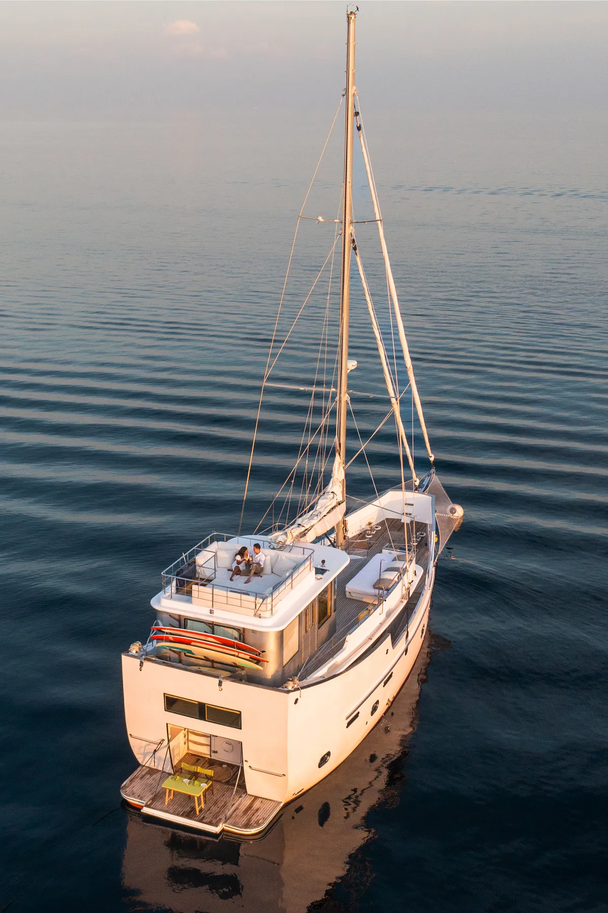 Soneva in Aqua chartered yacht moored over turquoise Noonu Atoll water under blue sky.