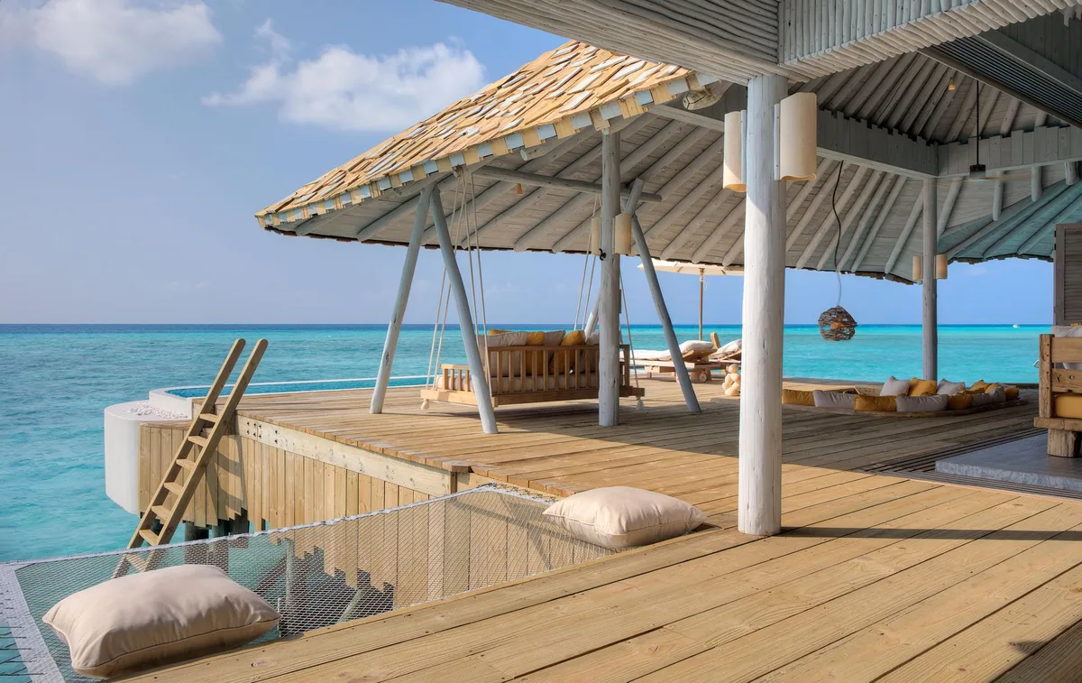 Soneva Secret, villa overwater, Haa Dhaalu Atoll, Maldives, Overwater pavilion deck: hanging daybed swings paired with the lagoon-edge plunge pool, open-air sun deck looking onto the turquoise reef-shallow water.