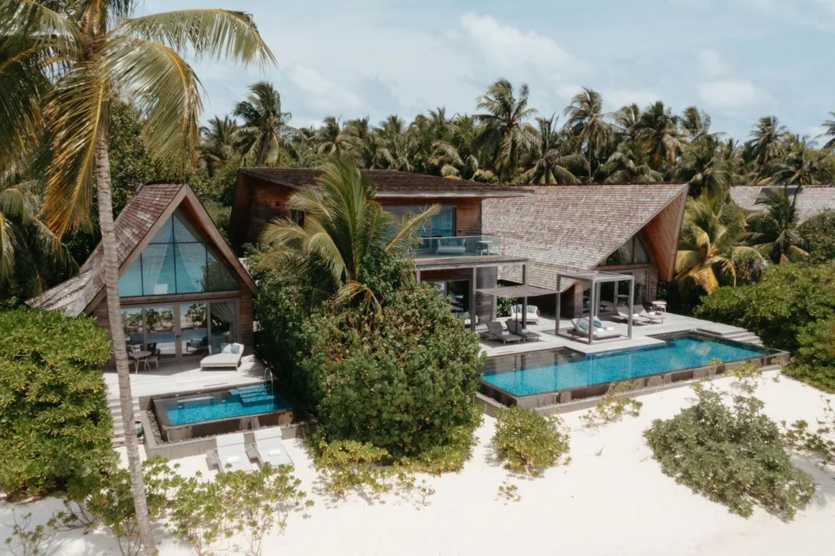 The St. Regis Maldives Vommuli Resort, villa beach, Dhaalu Atoll, Maldives, Beach Villa with Pool, close exterior: the angular timber-clad two-storey villa with sand-dune-inspired cantilevered roof, double-height glass to the lagoon, private pool at the beach edge. The signature Sand-Dune House architecture readable in one elevation.