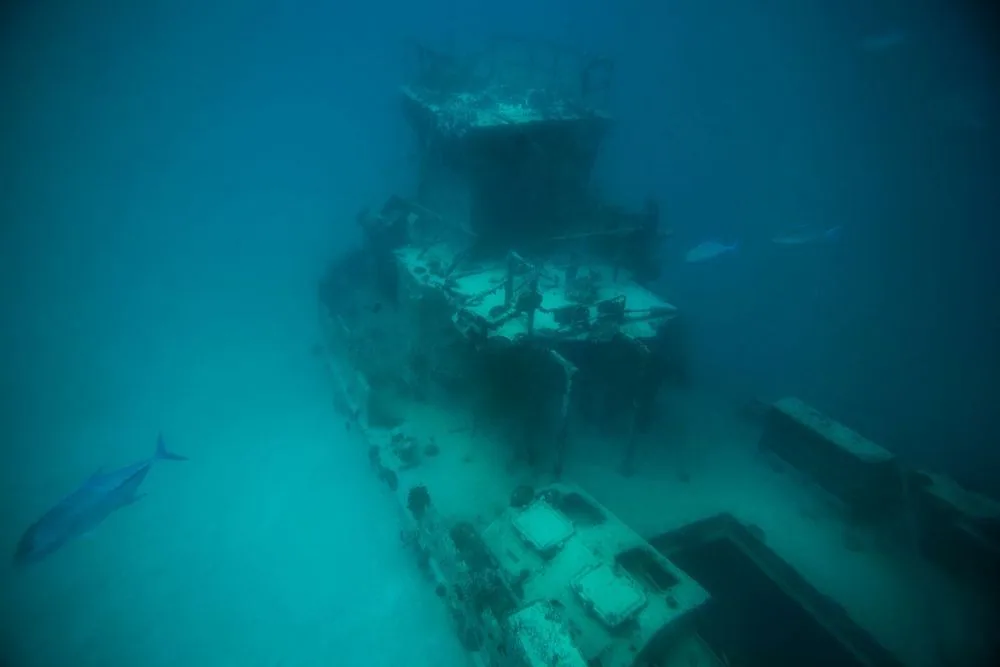 Taj Coral Reef Resort & Spa, activity, North Malé Atoll, Maldives, The on-doorstep shipwreck site, the sunken vessel resting on the white-sand lagoon bed at moderate depth with the structural bridge and cargo deck encrusted in marine growth, and reef fish tracking past in clear-blue visibility (the property's signature in-house-reef dive feature).