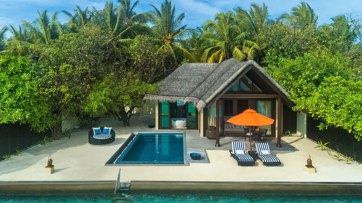 Taj Exotica Resort & Spa, Maldives, villa beach, South Malé Atoll, Maldives, Premium Villa with Pool exterior, a single thatched-roof beach pavilion fronted by a private rectangular pool, orange umbrella with two black-striped loungers, and a dense palm-canopy backdrop.