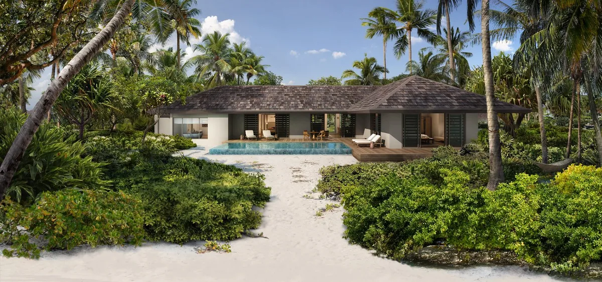 The Residence Maldives at Dhigurah, villa beach, Gaafu Alifu Atoll, Maldives, Beach Villa exterior from the beach approach, single grey-tile-roof villa with a private plunge pool and timber-deck dining set, sun lounger on the deck, palm canopy framing both wings of the villa.