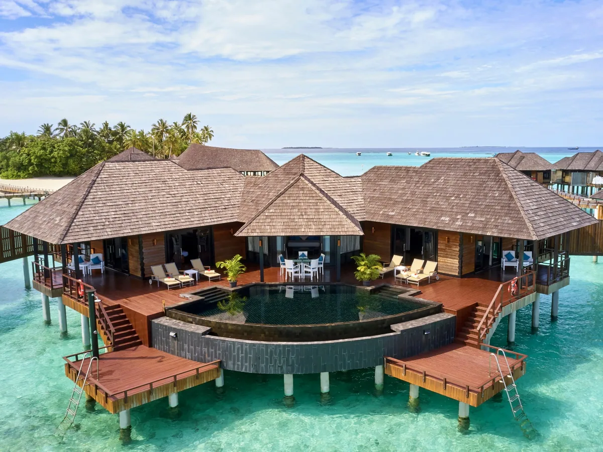 Sun Siyam Iru Fushi, Infinity Water Villa cluster with four pyramid-roof villas, dark-tile infinity plunge pool, sun loungers and boardwalk connections, Noonu Atoll, Maldives