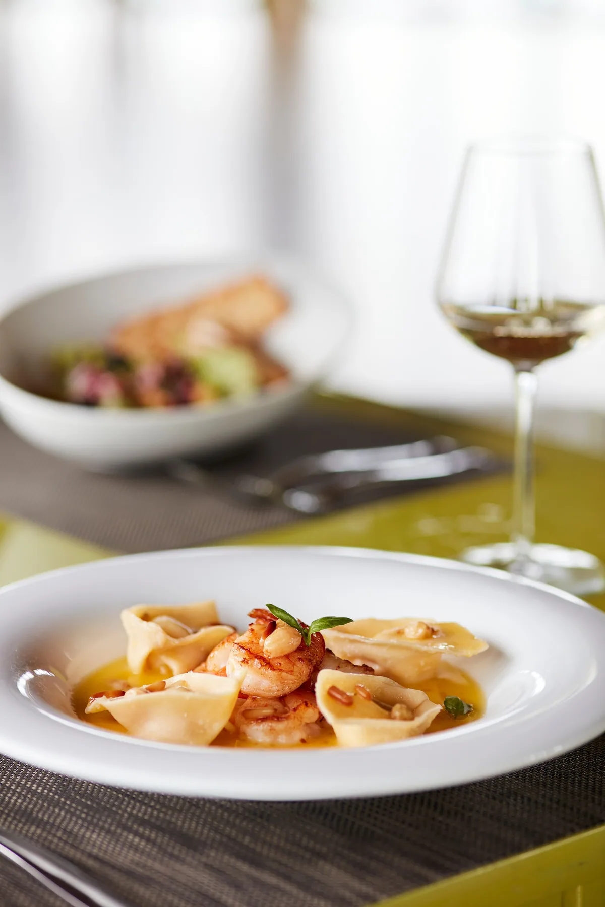 Sun Siyam Iru Fushi, Trio over-water Italian plated saffron pasta tortelloni with prawn, pine nuts and basil with white wine on green placemat, Noonu Atoll, Maldives