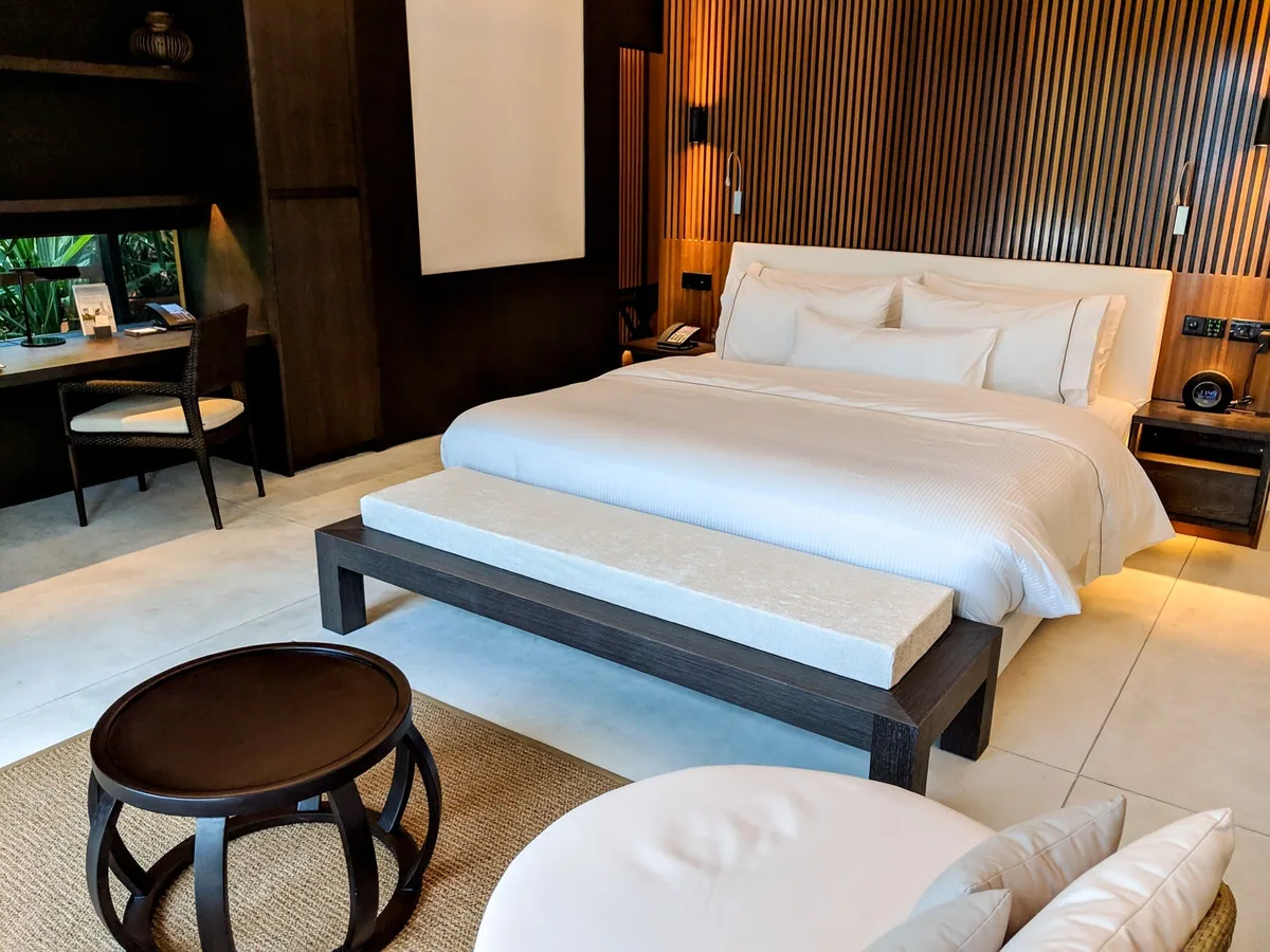 The Westin Maldives Miriandhoo Resort, villa beach, Baa Atoll, Maldives, Island Villa with Pool interior, the king Heavenly bed with white linen and the timber bench at the foot, slatted-warm-wood feature headboard wall and woven sisal rug on the polished-concrete floor, simple lined-natural-material modern design.