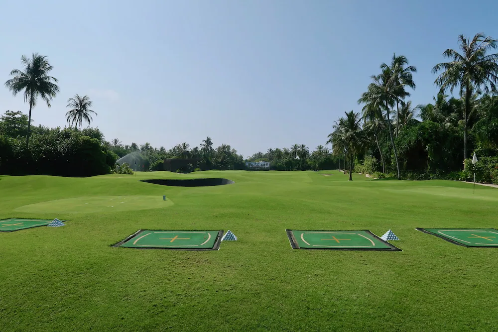 Velaa Private Island, activities, Noonu Atoll, Maldives, The Velaa Academy nine-hole pitch-and-putt driving range on a separate Noonu islet, four target tee boxes with orange cross markings and pyramid markers, manicured fairway framed by coconut palms.
