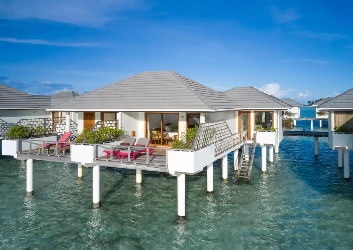 Villa Park Sun Island Resort, villa overwater, Alif Dhaal (South Ari) Atoll, Maldives, Sunrise Water Villa exterior with the grey pyramid-tile roof, the white-stilt platform over the turquoise lagoon, and the private deck with cushioned loungers at the eastern jetty cluster.