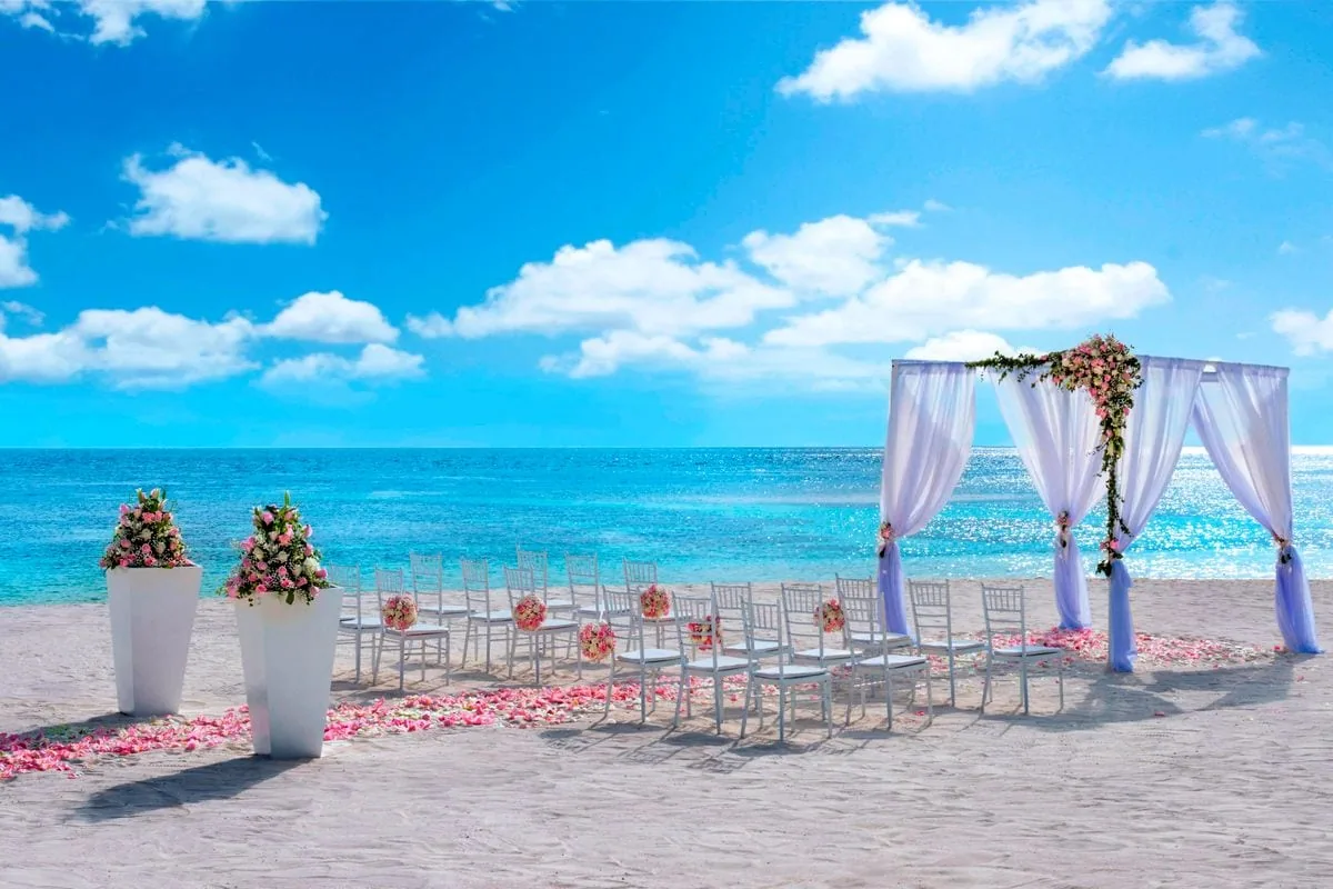 W Maldives, activities, Alif Dhaal (South Ari) Atoll, Maldives, Beach wedding chuppah with the white-drape arch carrying a pink-rose floral garland, the tiffany silver chivari chair line, and the pink rose-petal aisle on the white sand beach against the reef-fronted lagoon.