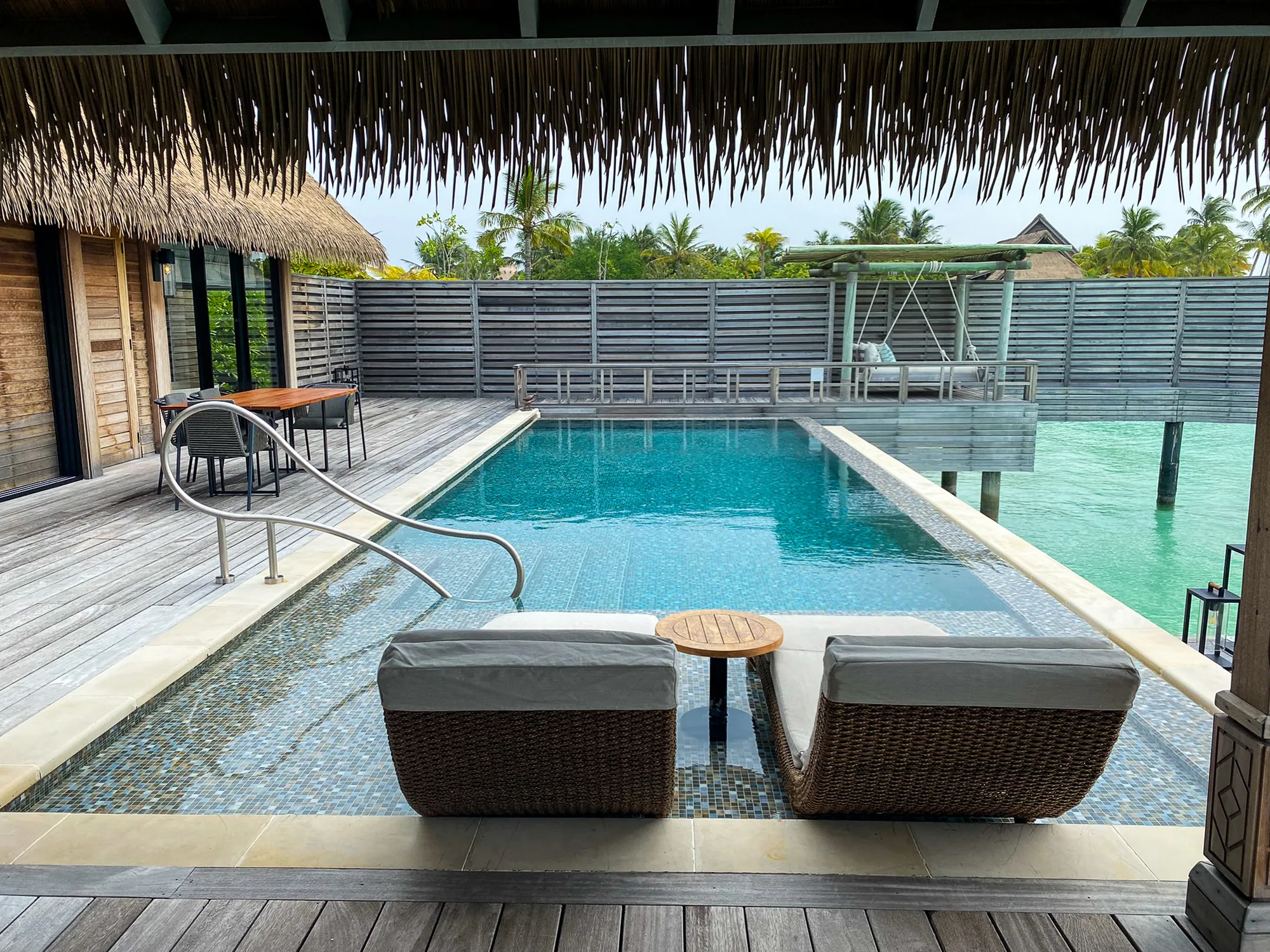 Waldorf Astoria Maldives Ithaafushi, villa reef, South Malé Atoll, Maldives, Reef Villa with Pool, private infinity pool wrapped by sun-bleached timber decking, two rattan wave loungers facing the lagoon under a thatched eave.